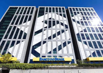 Uma ação judicial movida contra o Banco do Brasil desvela décadas de práticas ilícitas de venda casada no crédito rural. Conduzida pela Associação Brasileira de Defesa do Agronegócio (ABDAGRO), a ação busca indenizações totais de R$ 841 bilhões, revelando o desvio de bilhões de reais dos produtores rurais ao longo do tempo. A prática de venda casada, que é o foco da controvérsia, vincula a concessão de crédito rural à compra de produtos financeiros, como seguros e consórcios, prejudicando milhares de produtores desde a década de 1960. O Banco do Brasil, que detém uma significativa fatia do mercado de crédito rural, desviou recursos originalmente destinados ao agronegócio. Escândalo do Banco do Brasil Ao longo da última década, o Banco do Brasil concedeu R$ 1,5 trilhão em crédito rural, mas pesquisas indicam que R$ 179 bilhões foram desviados de forma ilegal para a aquisição obrigatória de produtos financeiros. Essa prática aumentou os custos operacionais dos produtores e afetou profundamente o financiamento agrícola no Brasil. A ação judicial contra o banco exige o pagamento de R$ 360 bilhões pela restituição dos valores desviados, R$ 150 bilhões por danos morais aos produtores, R$ 179,9 bilhões por danos sociais e R$ 50 bilhões por danos morais coletivos, totalizando R$ 841 bilhões. Ex-funcionários do banco confirmaram que a alta direção incentivava a prática da venda casada, estabelecendo metas de vendas que beneficiavam a instituição em prejuízo dos produtores. Repercussão O caso provocou investigações por parte de órgãos reguladores, como o Ministério Público Federal (MPF), o Banco Central (BC) e o Tribunal de Contas da União (TCU). Esse crime sistêmico perdurou por décadas devido à negligência dos órgãos responsáveis pela fiscalização. A ABDAGRO visa não só a reparação financeira, mas também a reformulação das normas que regem o crédito rural, garantindo que ele realmente apoie o setor agrícola. A ação é interpretada como uma luta pela dignidade dos produtores e pela manutenção do agronegócio, que desempenha papel crucial na economia do Brasil.