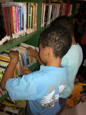 Crianças manuseiam livros de biblioteca comunitária implantada em Santa Luzia (MG)
