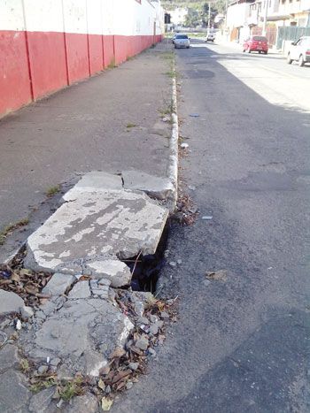 Tampa esfacelada e vergalhões expostos no passeio da Rua Delorme Louzada