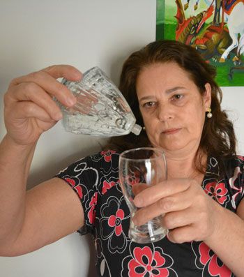 MARCELO RIBEIRO/08-10-14 Devota fervorosa, Marta Castro bebe a água benta armazenada em garrafa no formato da réplica de Nossa Senhora