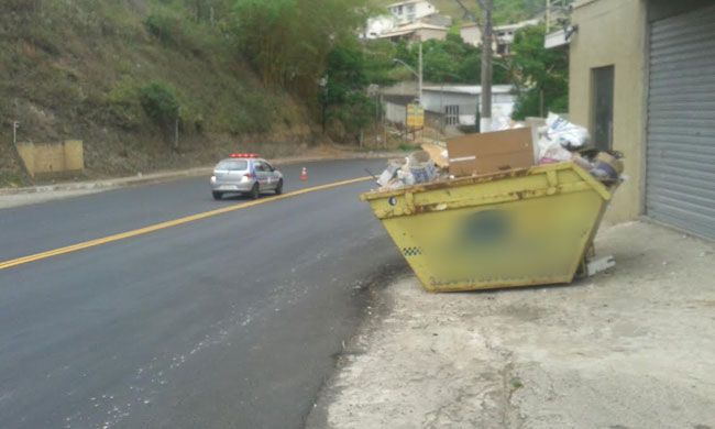 Além de dificultar passagem de pedestres na calçada, caçamba impediu recapeamento no acostamento (Marcos Cristian Costa)