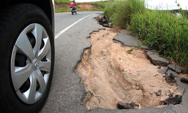 Cratera aumenta risco e mato dificulta visibilidade na via