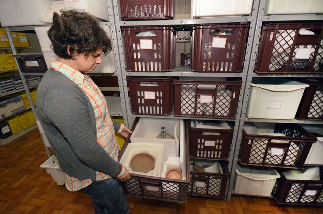 A pesquisadora Luciane mostra acervo em caixas armazenadas em uma sala do Arquivo Histórico da UFJF