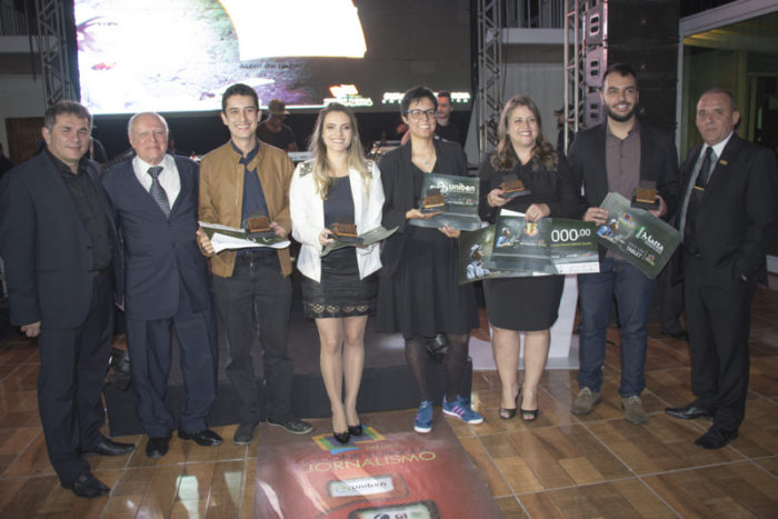  Dennis Orru, o homenageado Oddone Turolla e o presidente do Sindicomércio, Emerson Belloti ladeando os vencedores do Prêmio de Jornalismo, Eduardo Valente, Larissa Zimmermann, Roberta Oliveira, Désia Souza e Guilherme Arêas, que representou a estagiária da TM, Júlia Campos Foto: Guilherme Ovídio