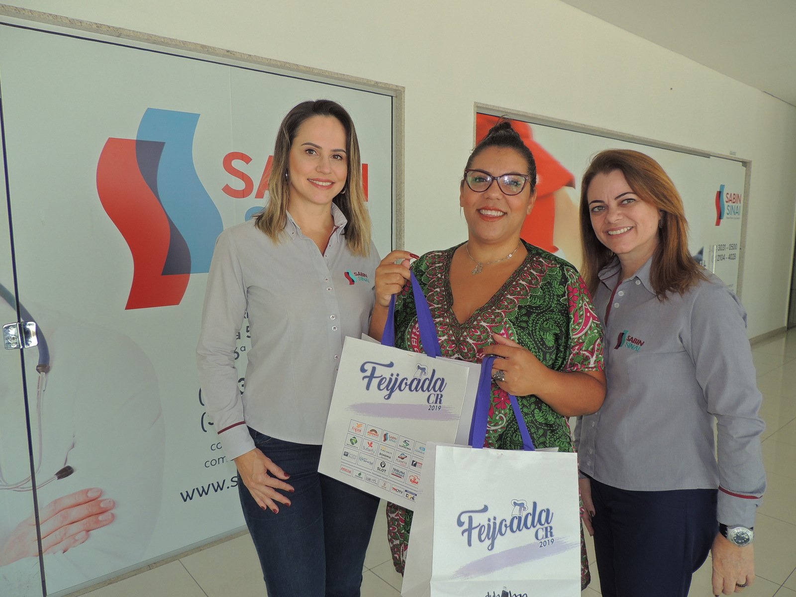 Sábado, dia de feijoada 1 Cláudia Teixeira e Andréa Poggianella ladeando Diana Pires, contemplada com duas camisetas da Feijoada 2019 na promoção do Instagram do Sabin Sinai, que teve mais de três mil comentários