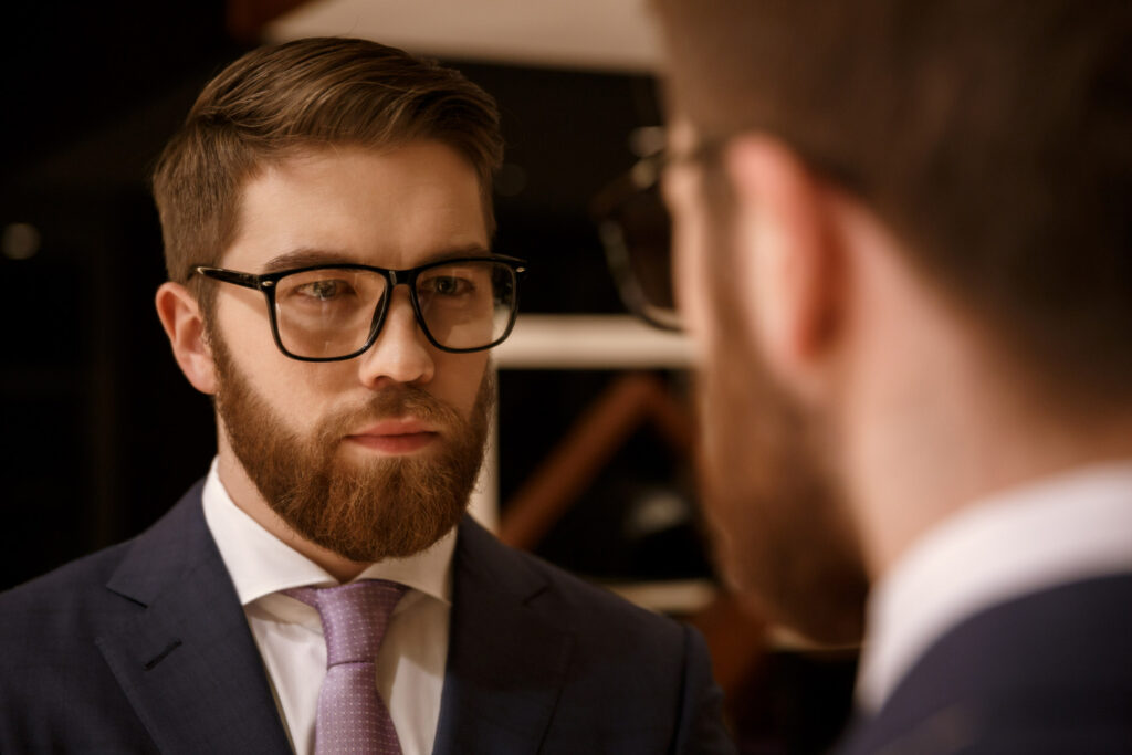 concentrated young bearded businessman looking at mirror 1