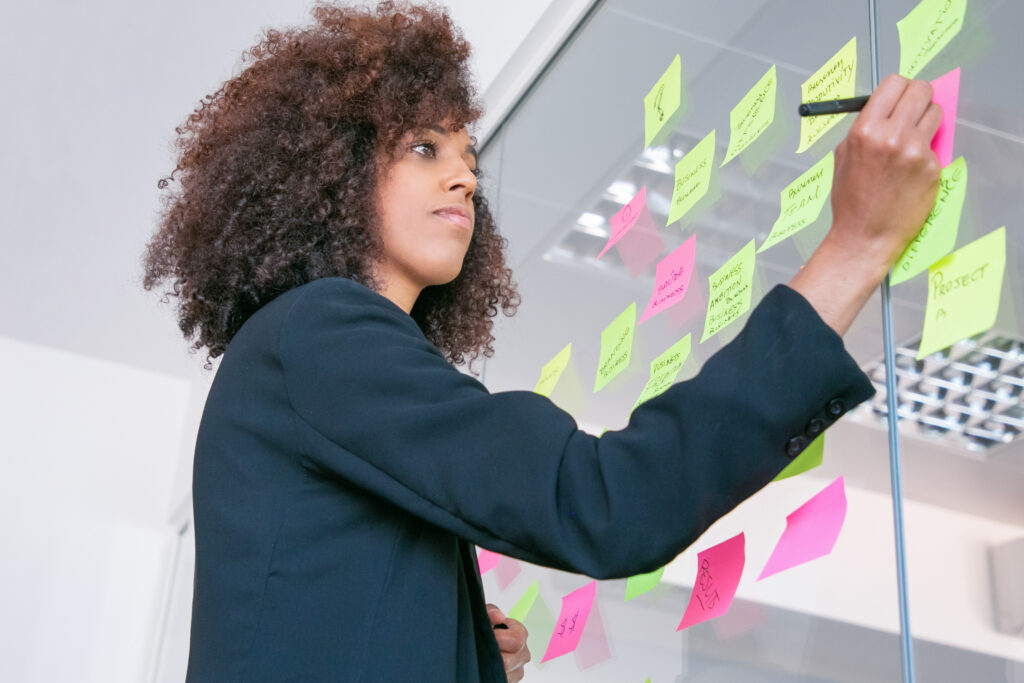 successful pretty businesswoman writing sticker with marker thoughtful confident curly female manager sharing idea project making note brainstorming business training concept