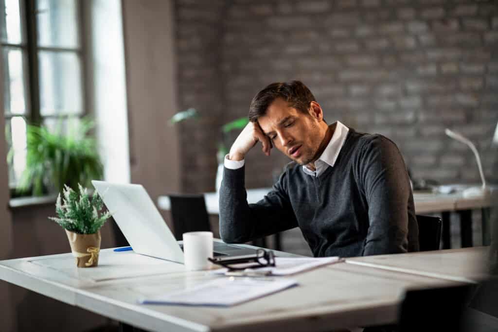 overworked businessman sitting at his desk and thinking of something in the office