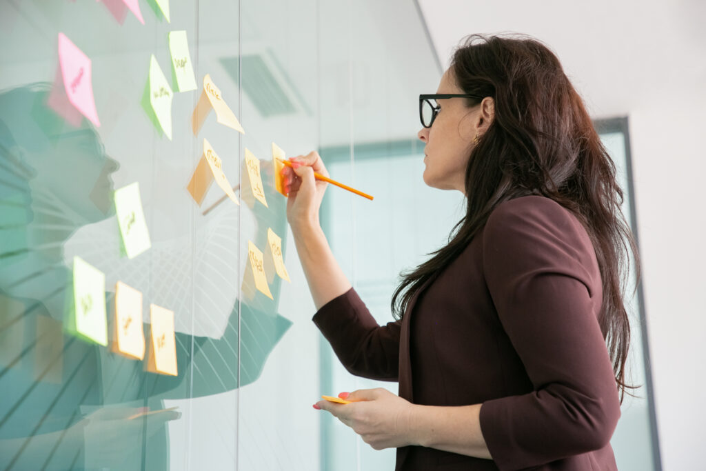 mulher de negocios de meia idade confiante escrevendo em um adesivo com lapis e brainstorming