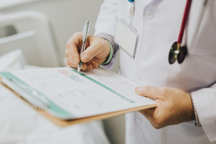 physician noting down symptoms patient