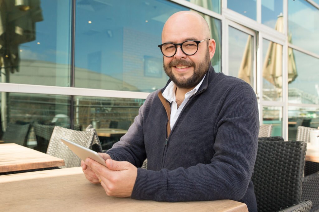 smiling middle aged man using tablet street cafe