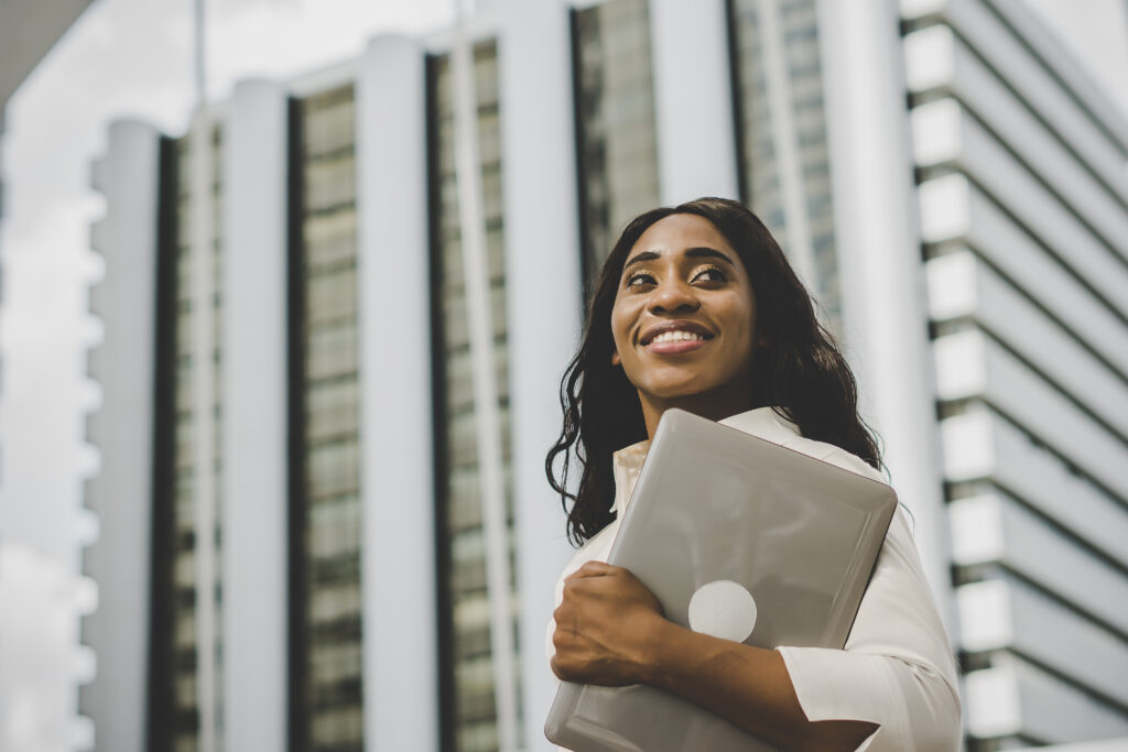 businesswoman holding laptop standing foreground business center