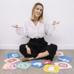 businesswoman sitting floor with social media icons shrugging