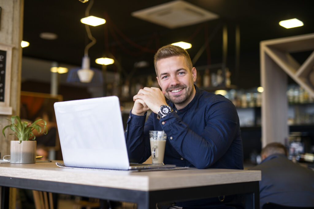 portrait smiling man sitting cafe bar with his laptop computer