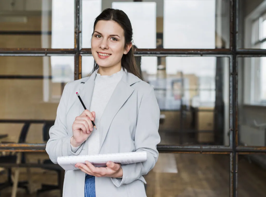 happy businesswoman looking camera with holding pencil diary
