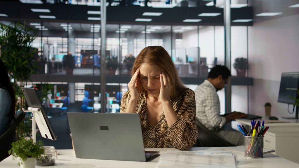 successful woman battles headache while managing her financial projects