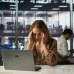 successful woman battles headache while managing her financial projects