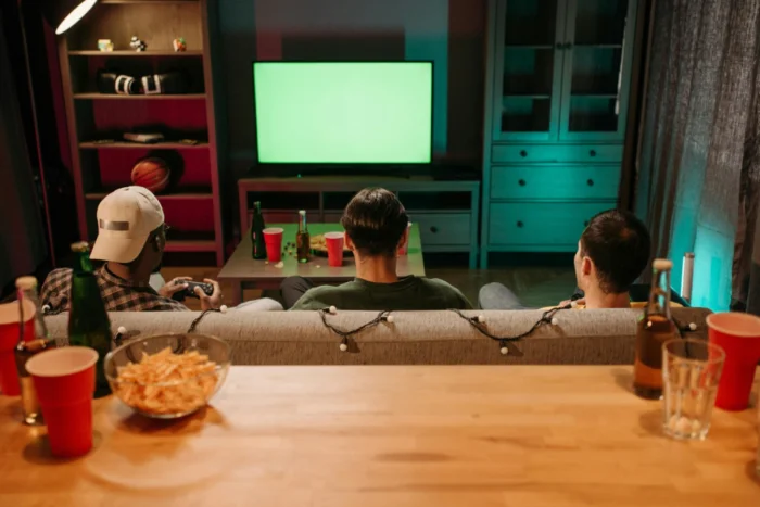 Mercado de apostas passa por nova fase de controle e fiscalização no Brasil 1 Grupo de amigos sentado em um sofá assistindo a um evento esportivo pela televisão, acompanhando a partida em um ambiente descontraído