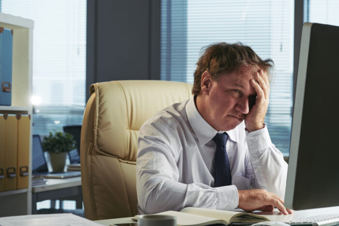 stressed man with headache working early morning his office scaled e1785243487343