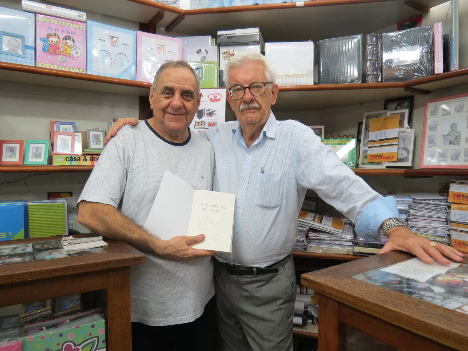 Higor Bastos e Amanda Manera clicados na mostra fotográfica dele, no Independência Shopping 2 José Carlos (Zé Kodak) Passos recebeu do jornalista Wilson Cid, o livro “À Margem do Paraibuna”